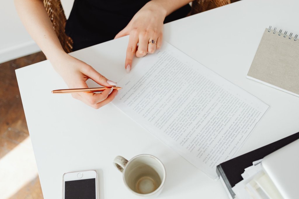emploi-et-handicap-une-proposition-de-loi-contre-les-discriminations-2 Vue de dessus d’une femme pointant un document sur un bureau blanc, un stylo à la main
