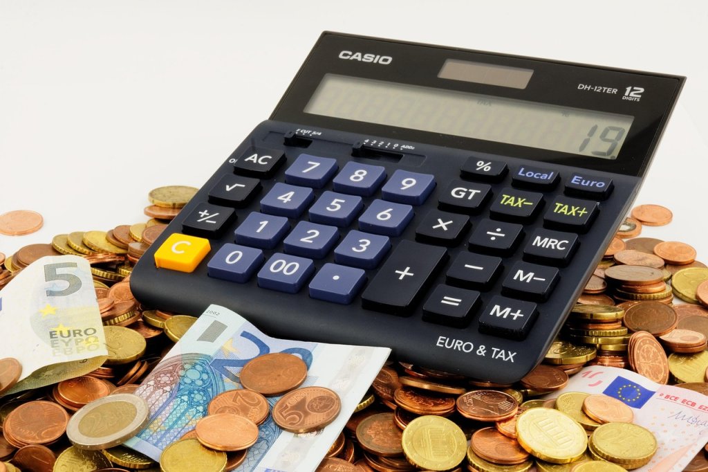 fin-du-cumul-ass-aah-jusqu-a-600-euros-mensuels-en-moins-des-2027 Calculatrice posée sur des billets de 5 et 20 euros entourés de pièces de monnaie
