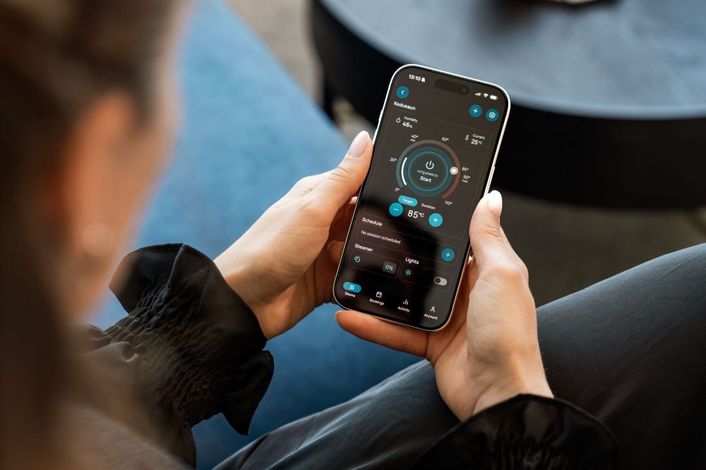 14-innovations-pour-renforcer-autonomie-et-accessibilite-au-quotidien-2 Une femme tient un smartphone affichant une application de contrôle de sauna